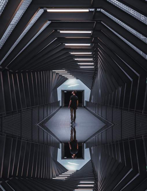 Person standing in a mirrored hallway looking around